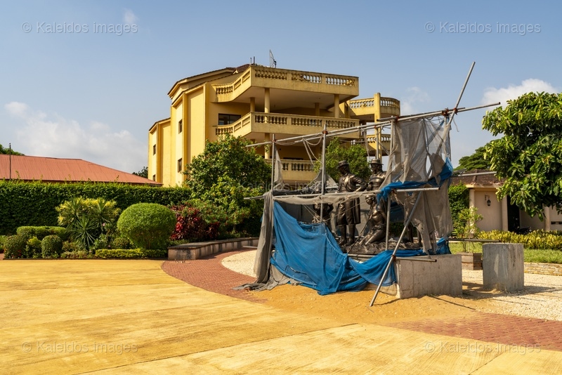 Place des Enchères Ouidah ; Place Chacha slave market Benin ; bronze sculptures slave trade ; spheres ground memorial Ouidah ; monumental heads Xweda Fon Yoruba ; memorial public art West Africa ; night lighting Ouidah square ; red laterite ground ; de Souza house Singbomey ; Afro-Brazilian heritage Ouidah ; Benin Revealed program