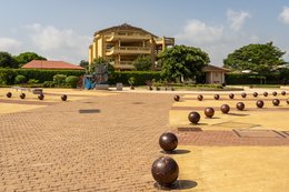 Place-des-Enchères-Ouidah-;-Place-Chacha-slave-market-Benin-;-bronze-sculptures-slave-trade-;-spheres-ground-memorial-Ouidah-;-monumental-heads-Xweda-Fon-Yoruba-;-memorial-public-art-West-Africa-;-night-lighting-Ouidah-square-;-red-laterite-ground-;-de-Souza-house-Singbomey-;-Afro-Brazilian-heritage-Ouidah-;-Benin-Revealed-program