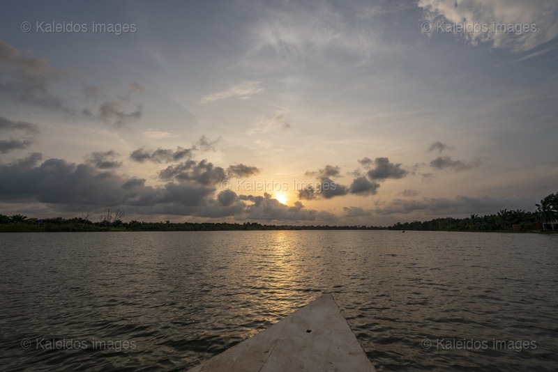 Lake Toho;Ouidah;Benin;West Africa;sunset;golden hour;pirogue;bow;orange sky;clouds;light reflection;lake crossing;point of view;travel;West Africa landscape;Tarek Charara;Kaleidos;Kaleidos images;La parole à l'image