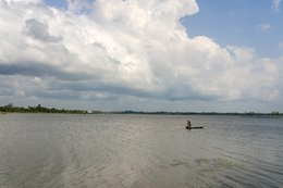 Lake-Toho;Ouidah;Benin;West-Africa;fisherman;pirogue;standing;paddle;cumulus;dramatic-sky;open-water;water-lily;lake-landscape;traditional-fishing;solitude;Tarek-Charara;Kaleidos;Kaleidos-images;La-parole-à-limage