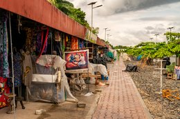-Artisan-market;-Benin;-Cotonou;-Craft-stall;-Gbegamey;-Kaleidos;-Kaleidos-images;-La-parole-à-limage;-Marché-des-arts;-Painted-canvas;-Paved-walkway;-Railway;-Red-fascia-band;-Tarek-Charara