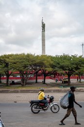 Benin;-Cotonou;-Daily-life;-Helmet;-Kaleidos;-Kaleidos-images;-La-parole-à-limage;-Monument;-Motorcycle-taxi;-Pedestrian;-Place-de-lÉtoile-Rouge;-Red-star;-Sack;-Statue;-Stories-Pictures;-Street-scene;-Tarek-Charara;-Urban-transport;-West-Africa;-Zemidjan