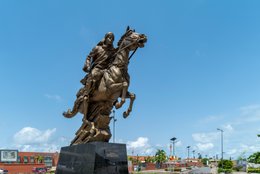 Advertising-sign;-Benin;-Bio-Guéra;-Cast-copper;-Clear-sky;-Commercial-building;-Cotonou;-Equestrian-statue;-Erevan-junction;-Golden-patina;-Historical-heritage;-Horseman;-Kaleidos;-Kaleidos-images;-La-parole-à-limage;-Monument;-Rearing-horse;-Sculpture;-Tarek-Charara;-Wasangari-prince;-West-Africa
