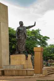 Abomey;-Béhanzin;-Benin;-Bronze;-Colonial-resistance;-Cultural-heritage;-Dahomey;-Kaleidos;-Kaleidos-images;-King;-La-parole-à-limage;-Mansudae;-Monument;-Pagne;-Passersby;-Place-Goho;-Sculptural-detail;-Sculpture;-Side-view;-Statue;-Stories-Pictures;-Tarek-Charara;-Vegetation