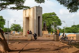Abomey;-Béhanzin;-Benin;-Bicycles;-Colonial-resistance;-Cultural-heritage;-Dahomey;-Everyday-life;-Kaleidos;-Kaleidos-images;-King;-La-parole-à-limage;-Mansudae;-Monument;-Motorbikes;-Passersby;-Place-Goho;-Public-space;-Stories-Pictures;-Tarek-Charara;-Urban-context;-Urban-scene